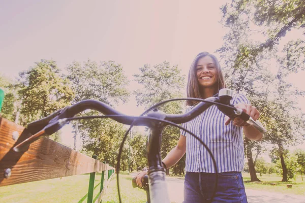 Pretty młoda kobieta jazda rowerem w parku — Zdjęcie stockowe