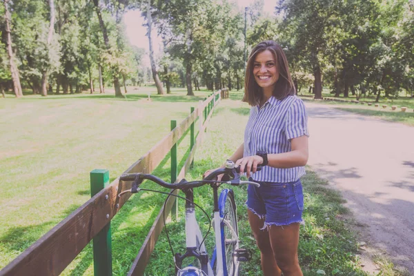 Krásná mladá žena jízda na kole v parku — Stock fotografie