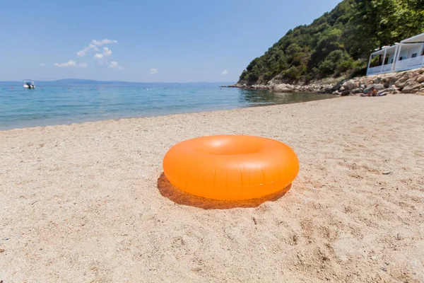 Anillo inflable amarillo para nadar en la playa de arena en el día de verano —  Fotos de Stock