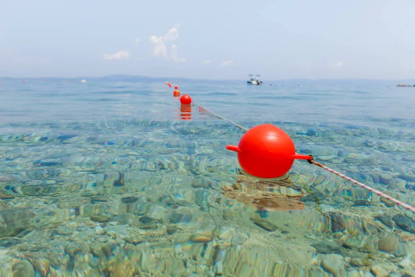 Boa rossa galleggiare sulla superficie del mare turchese chiaro — Foto Stock