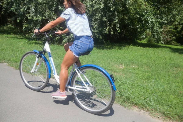 Bastante joven mujer montando bicicleta en el parque vista trasera — Foto de Stock