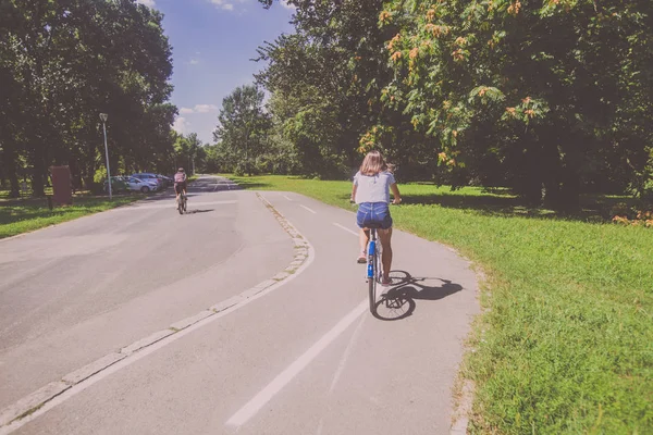 Bonita jovem mulher andar de bicicleta no parque vista traseira — Fotografia de Stock