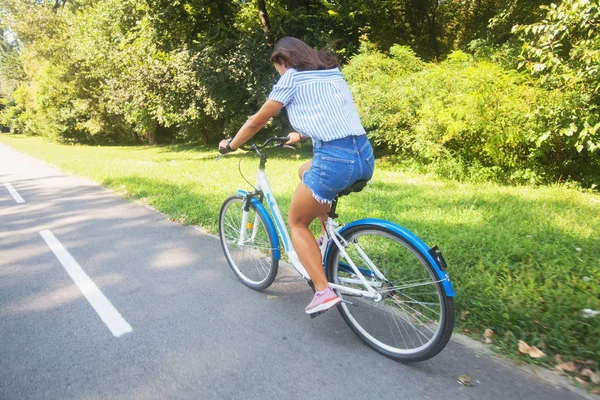 Bastante joven mujer montando bicicleta en el parque vista trasera — Foto de Stock