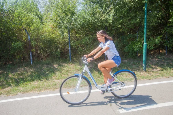 公園で自転車に乗っている若い女性は — ストック写真