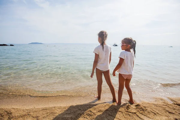 Deux petites filles debout ensemble sur la plage de sable — Photo