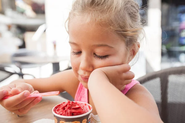 Милая маленькая девочка ест мороженое на открытом воздухе кафе — стоковое фото