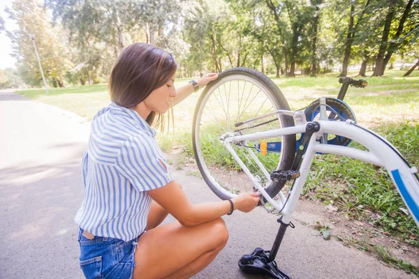 Junge Frau überprüft ihr Fahrrad — Stockfoto