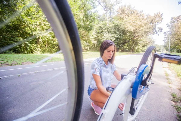 Jovem mulher verificando sua bicicleta — Fotografia de Stock