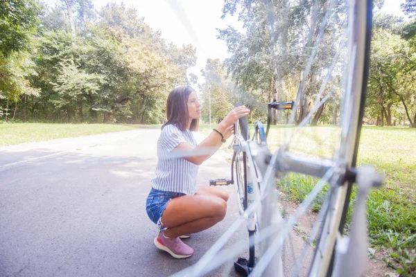 Junge Frau überprüft ihr Fahrrad — Stockfoto