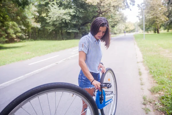 Jovem mulher verificando sua bicicleta — Fotografia de Stock