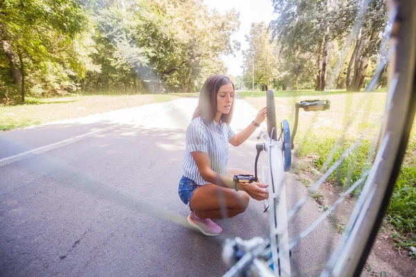 Молодая женщина проверяет свой велосипед — стоковое фото