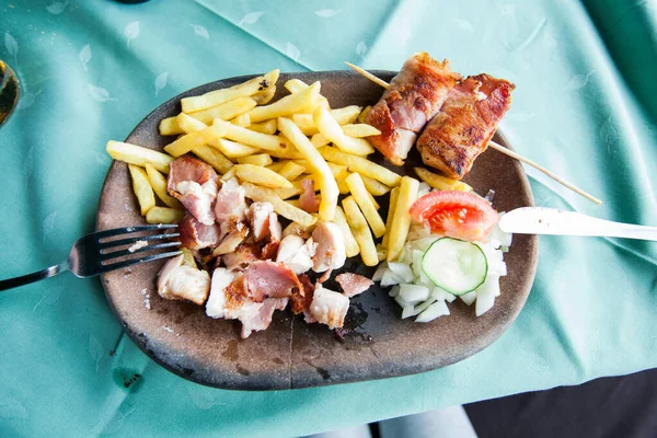 レストランのテーブルで素朴なプレートにフランスのフライドポテトと玉ねぎとおいしいグリルポーク肉 — ストック写真