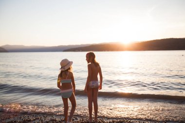 Çocuklar gün batımında sahilde eğlenirler. 