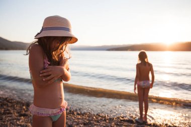 Çocuklar gün batımında sahilde, güzel yaz güneşi yansıması suya. 