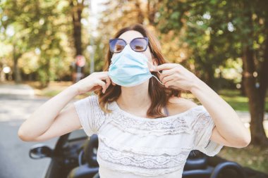 Koronavirüse karşı koruyucu maske takan çekici genç bir kadın.