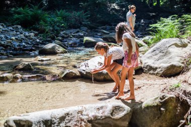 Mutlu çocuklar yaz ormanlarında dağ deresinde eğleniyorlar. Doğal gün ışığı. Macera.
