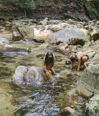 Mutlu çocuklar yaz ormanlarında dağ deresinde eğleniyorlar. Doğal gün ışığı. Macera.