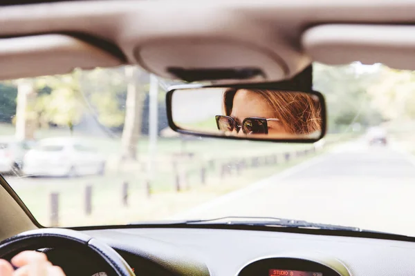 サングラスをかけて女性ドライバーの車のリアビューミラーに反射します 夏の日にコンバーチブル車を運転女性 — ストック写真