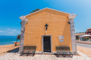 Güneşle sırılsıklam olmuş sahiller ve durgun turkuaz sularla kaplı geleneksel bir Yunan Ortodoks kilisesinin sakin bir görüntüsü..