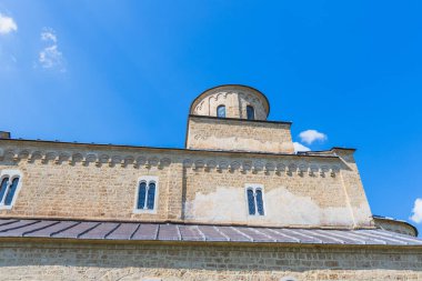 Ortaçağ taş manastırı kubbesi, haçı, kemerli pencereleri, parlak mavi gökyüzünün altında, Bizans Ortodoks Ortodoks Ortodoks Hıristiyan mirası ve huzurlu Doğu Avrupa kırsal manzarası sergileniyor. Studenica, Sırbistan.