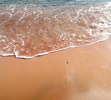 Kumlu sahilde yumuşak dalgalar