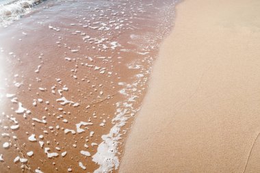 Kumlu sahilde yumuşak dalgalar