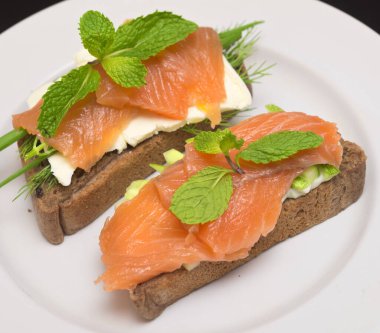 Tabağında kırmızı balık olan iki sandviç.