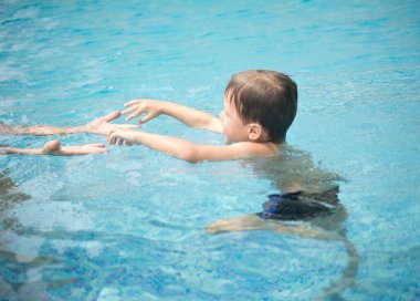 Çocuk annesiyle birlikte yüzme havuzunda.