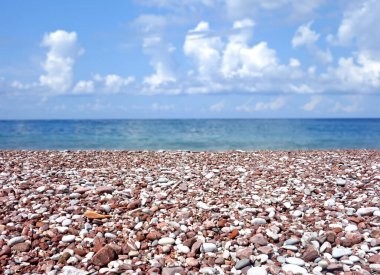 Bulanık deniz ve gökyüzü ile taştan kumsal