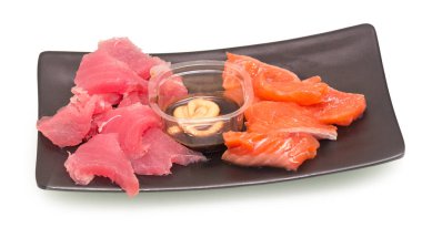 Somon ve ton balıklı saşimi siyah tabakta sos ve hardal beyaz arka planda.