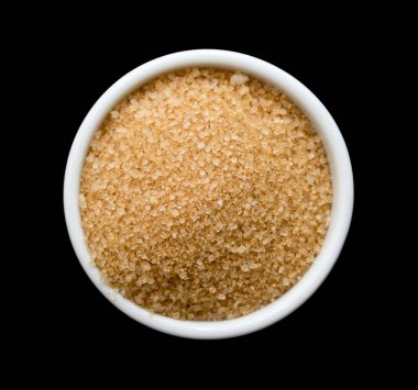 Siyah arka planda beyaz kasede kahverengi kamış şekeri