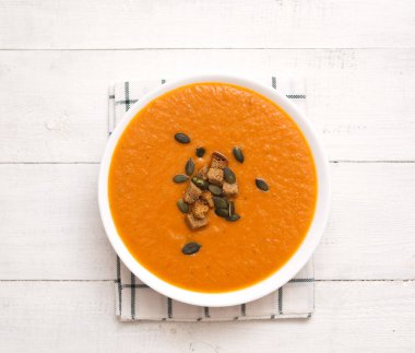 Balkabağı tohumlu domates kremalı çorba ve ahşap arka planda krakerler.