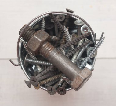 Tahta bir arka planda bir kovada vidalar ve cıvatalar