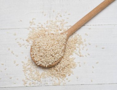 Tahta arka planda kaşık içinde susam