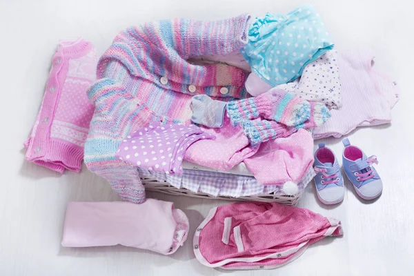 various baby clothes in a box on wooden table, top view