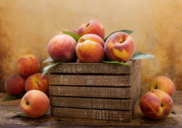 fresh peaches with leaves in a wooden box