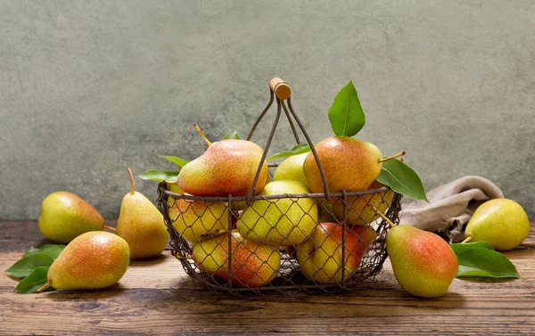 fresh pears with leaves in a basket on wooden table