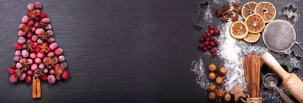 Christmas food. Ingredients for cooking Christmas baking: fir tree made from frozen cranberries and cinnamon sticks, kitchen utensils on a dark table, top view