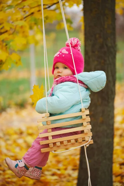 Petite fille sur balançoires dans le parc d'automne — Photo