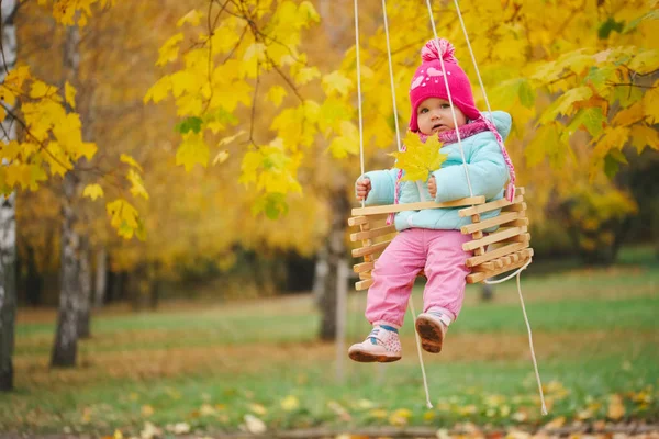 Little girl on swings in autumn park — Stock Photo, Image