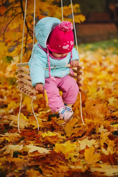 Menina em balanços no parque de outono — Fotografia de Stock