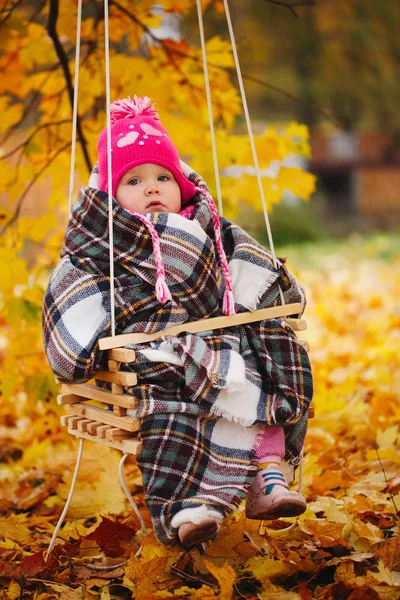 Маленька дівчинка на гойдалках в осінньому парку — стокове фото