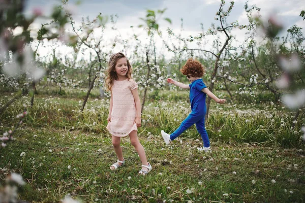 Niño y niña en el jardín floreciente —  Fotos de Stock