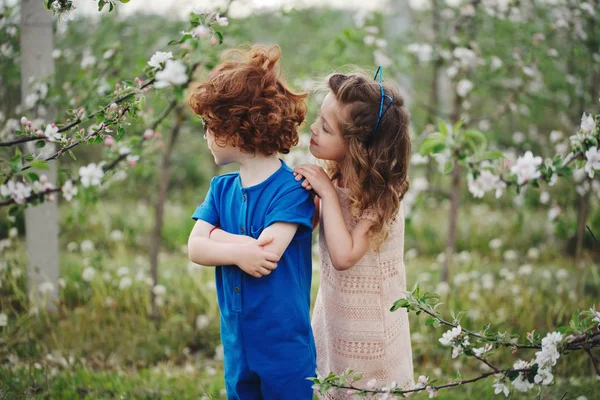 Niño y niña en el jardín floreciente — Foto de Stock