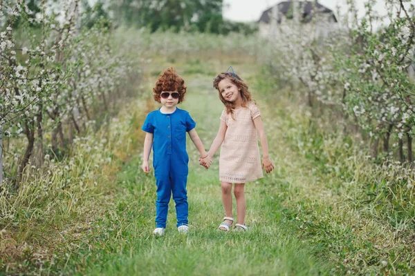 Μικρό αγόρι και κορίτσι σε ολάνθιστο κήπο — Φωτογραφία Αρχείου