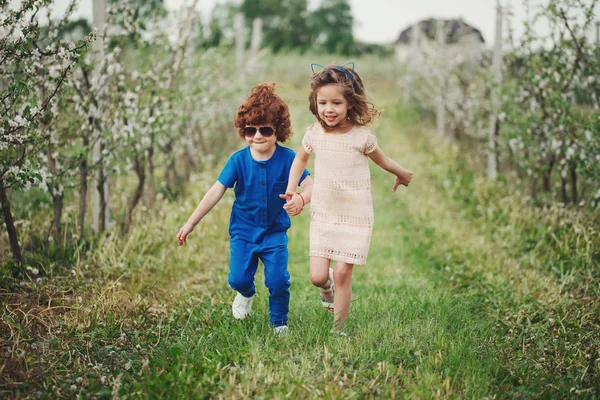 Mały chłopiec i dziewczynka w kwitnący ogród — Zdjęcie stockowe