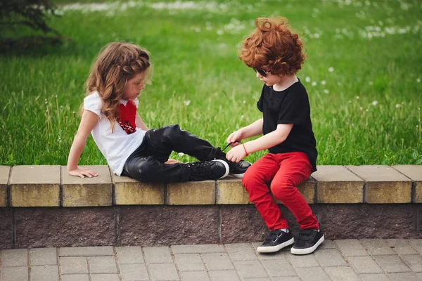 Boy helps little girl tie shoelaces — Stock Photo, Image