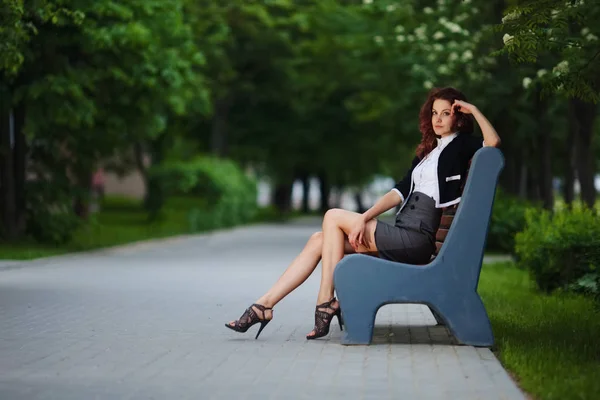 Mooi meisje zittend op bankje in park — Stockfoto