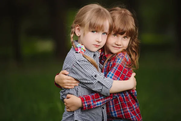 Two girls hugging each other on green — Stock Photo, Image