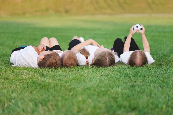 Anak-anak bahagia berbaring di lapangan sepak bola — Stok Foto